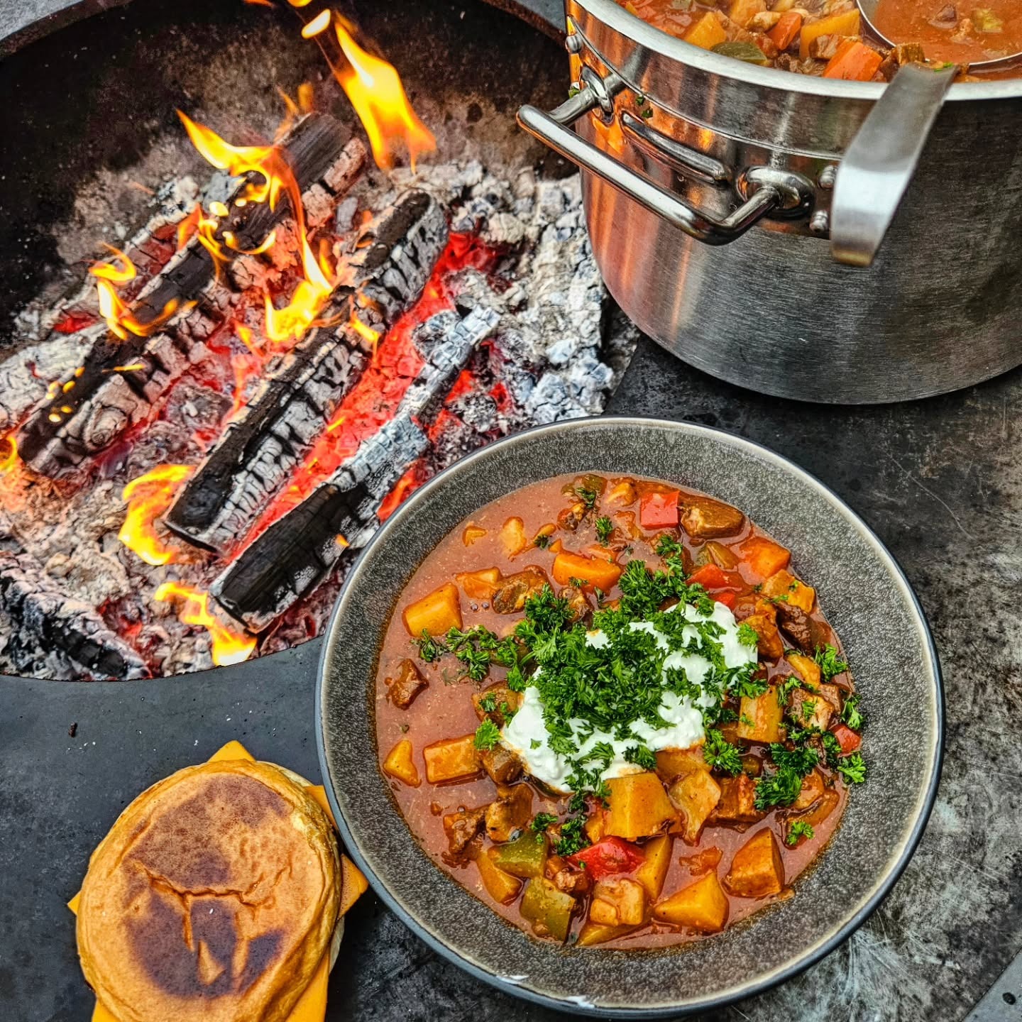 Gulasch bredvid en brasa och kastrull